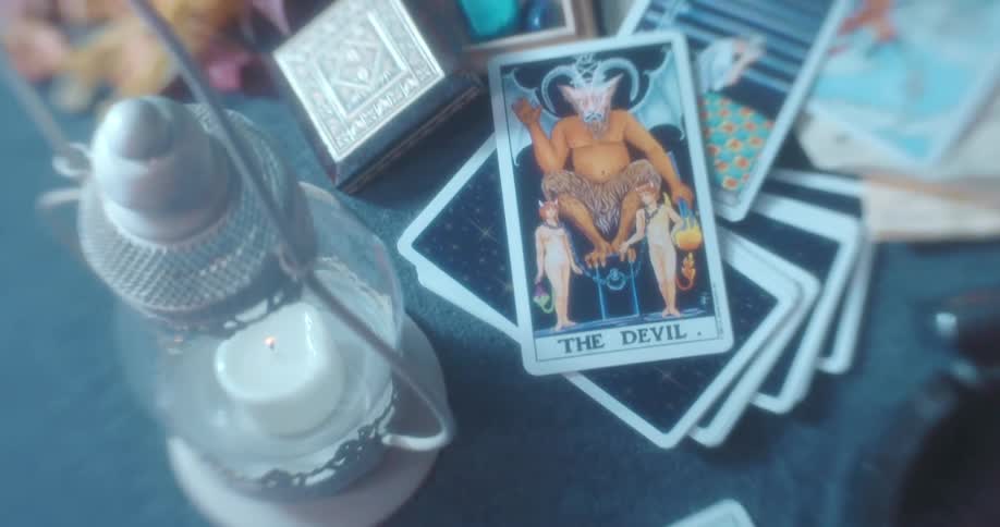 Set of tarot cards over a table next to a candle lamp in a room