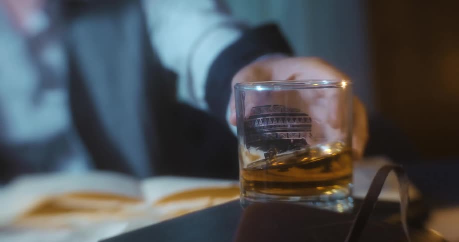 A person setting down a glass with an alcoholic liquid inside