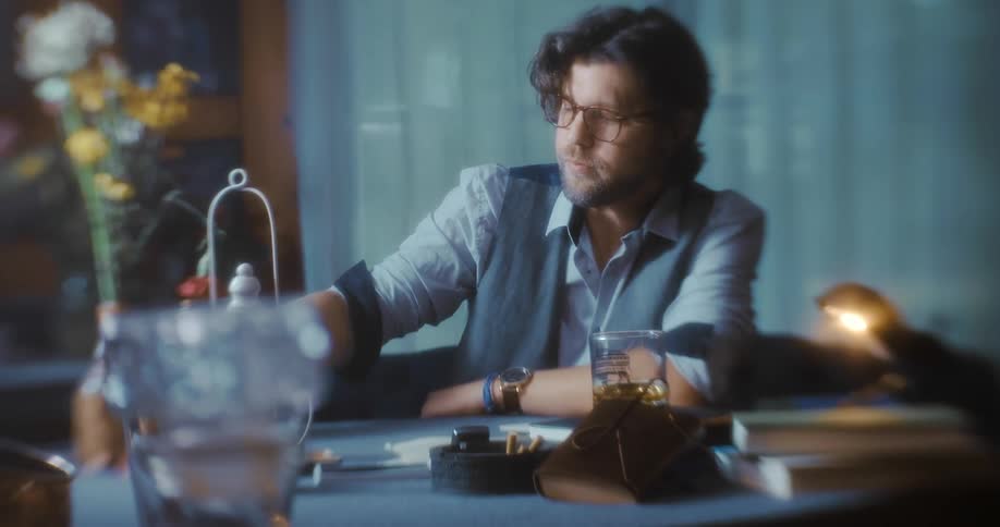 A man drinks and plays cards at the table