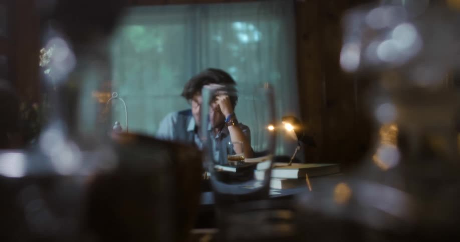 A man sits at a desk in deep thought looking downward