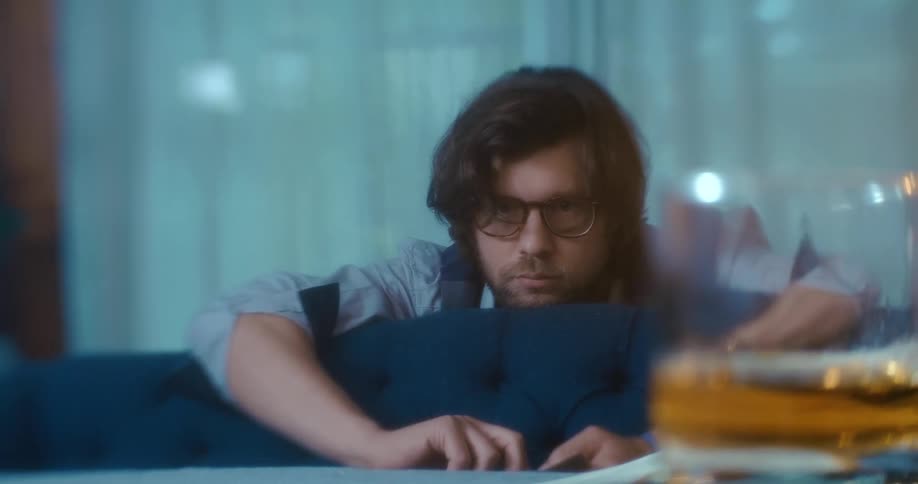 A man leans over a couch and throws cards on to a table