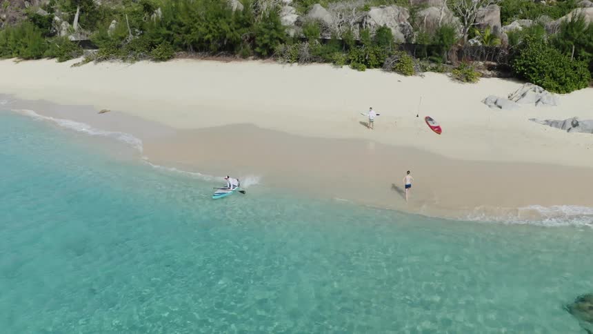 A wide shot of a group of people on a beach getting ready to surf
