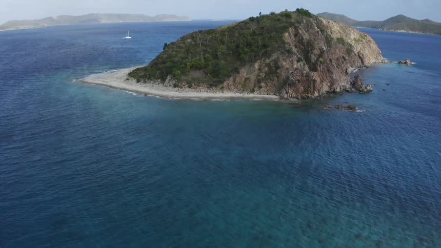 An aerial view of a boat sailing past an island
