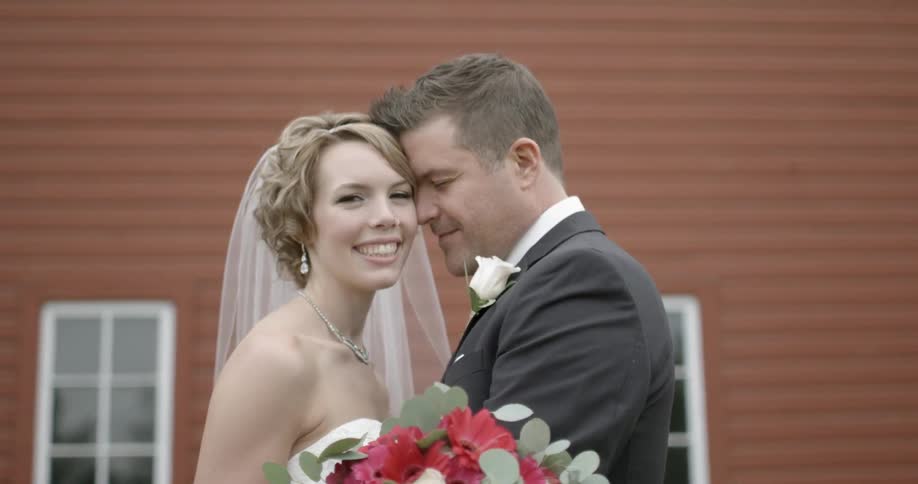 A bride and groom embrace as they stand outdoors