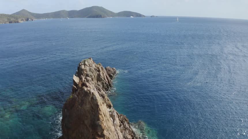 Waves crash onto the side of small islands in the ocean