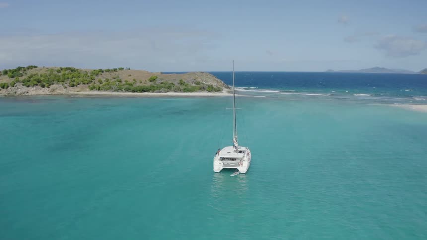 Aerial view of a catamaran resting in a tropical bay next to the ocean