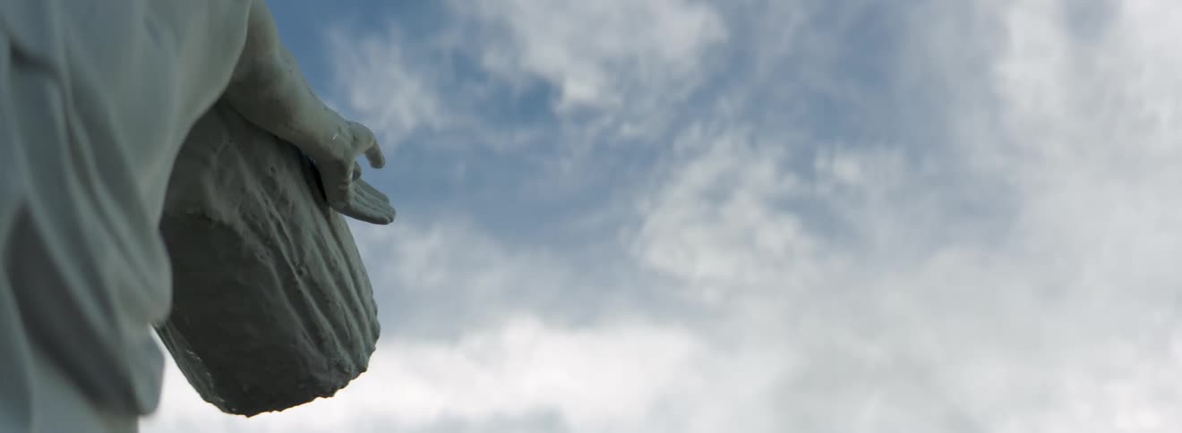 Half of a statue shown with a cloudy sky overhead in the afternoon