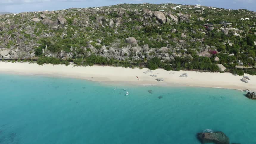 Two people push their canoes off the shore of a beach and paddle in the ocean
