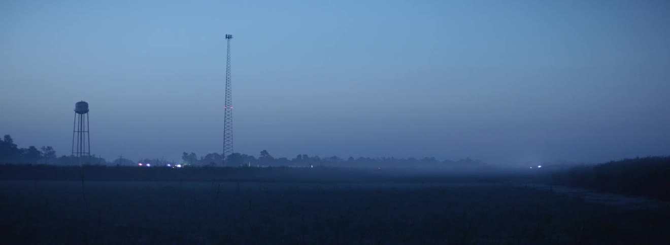 Mist over water and antenna towers in the calm fields on a rural area at evening