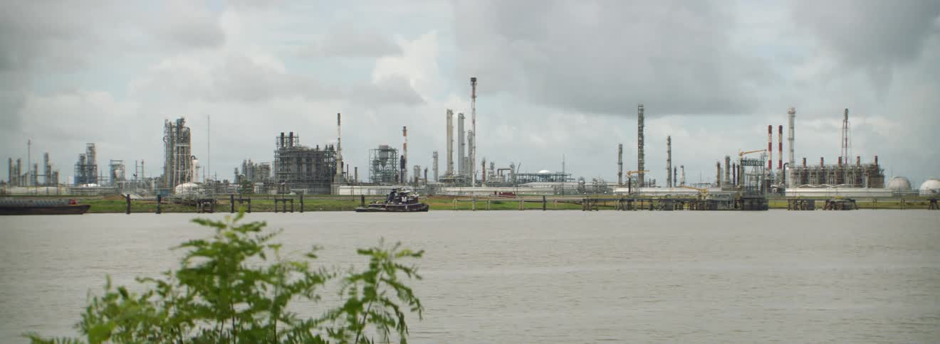 An industrial area or refinery is on the shoreline of a body of water