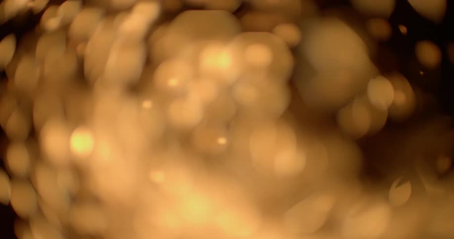 Gold confetti blows around in a closed circular space