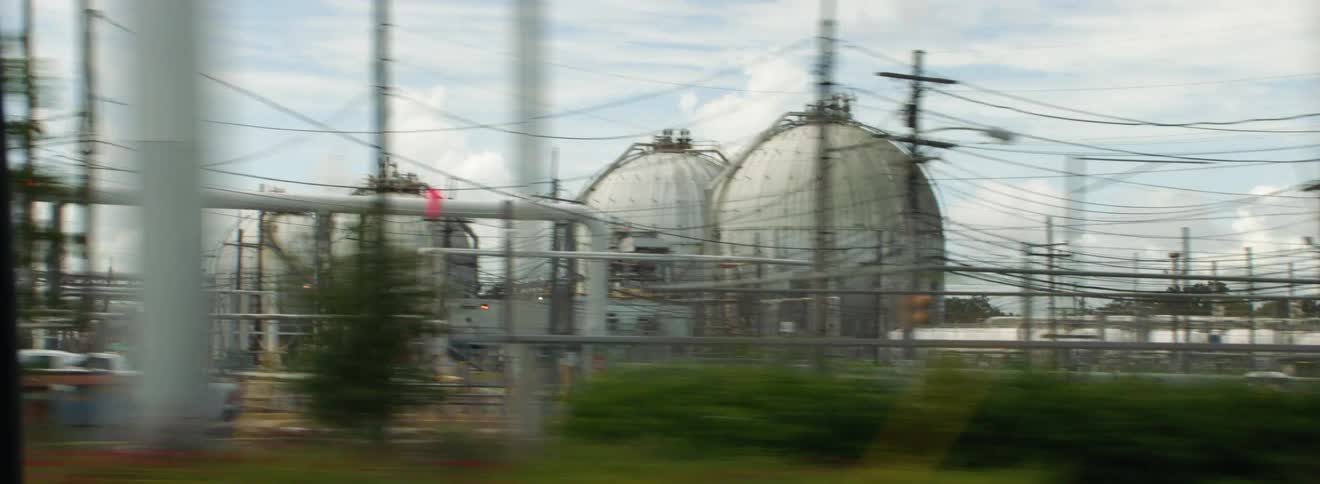 A power plant with pipes smoke buildings white trucks and heavy machinery takes up a huge area of land