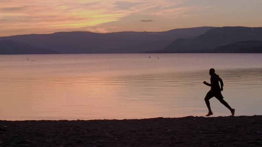 A man runs on the beach at sunrise