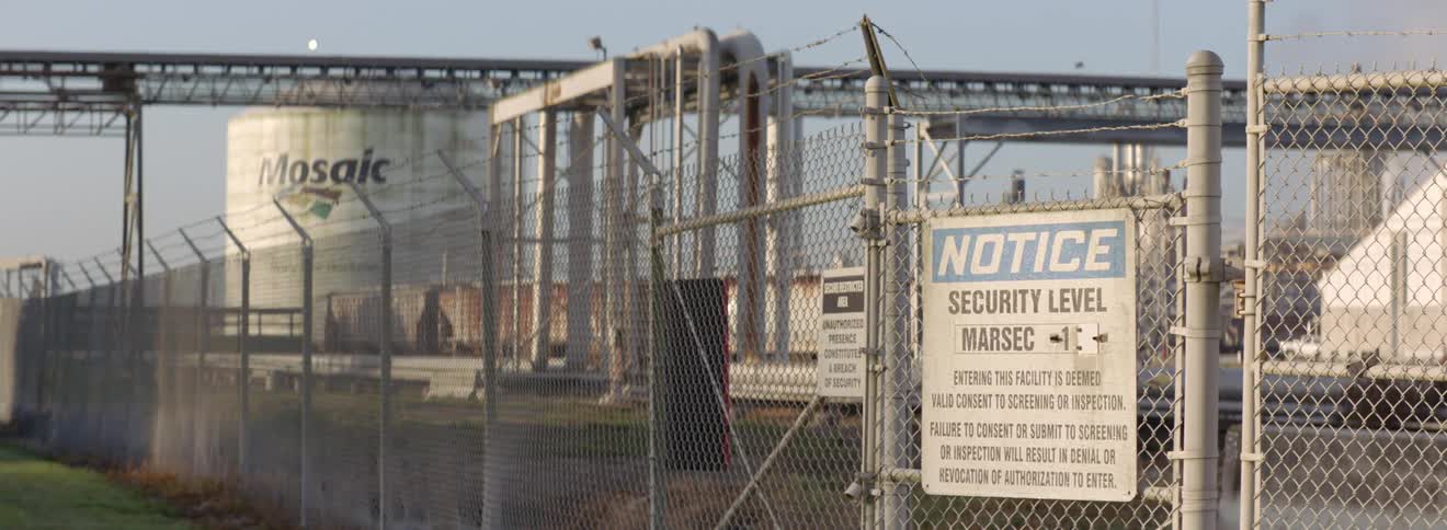 A sign posted on the face outside of a processing facility contains a warning about security