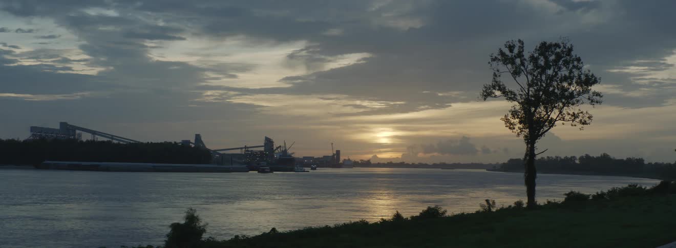 The sun sits low in the sky and shines over a body of water