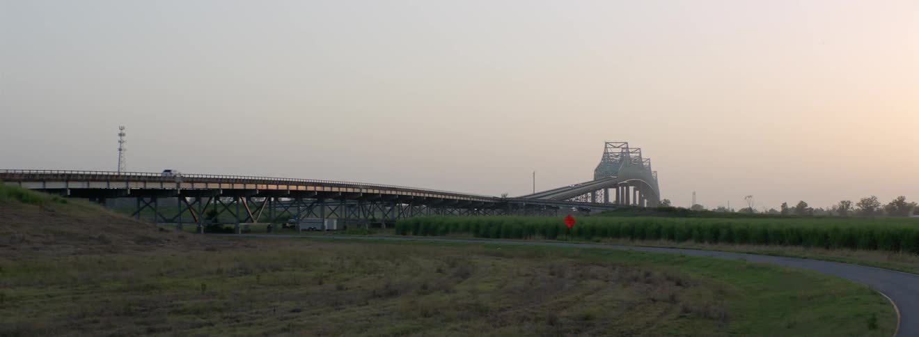 Vehicle driving over a bridge in a rural area at sunset