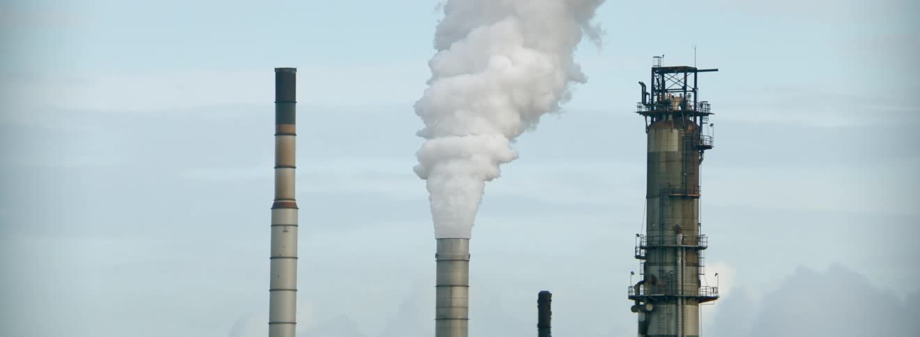 Thick smoke billows from a smokestack at a factory