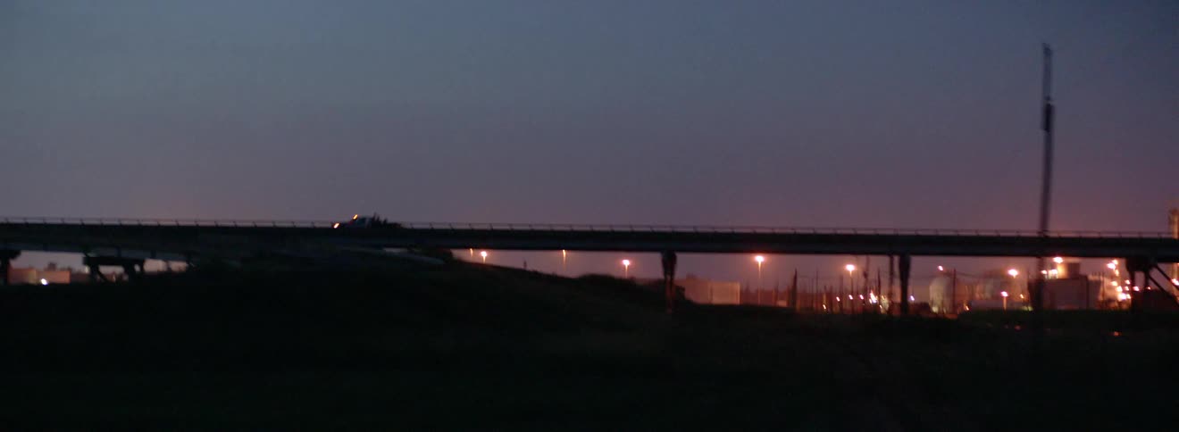 A bridge at night with traffic against a city