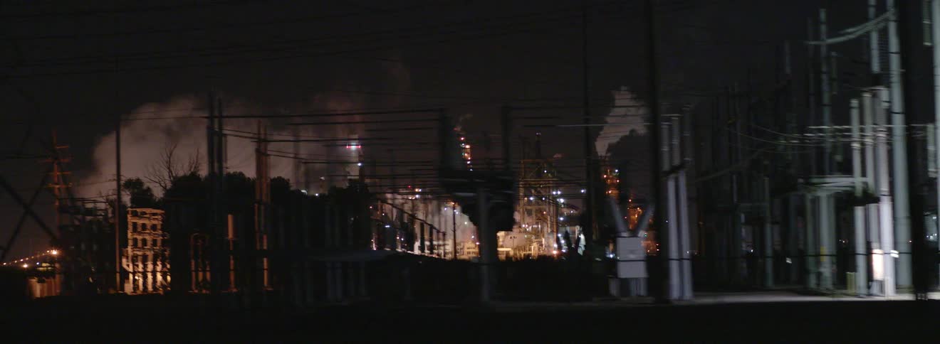 Night lights on an industrial complex spewing smoke