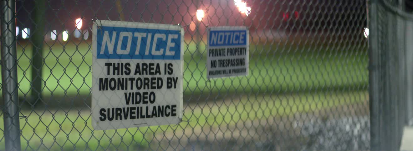 A chain linked fence has a couple of signs posted indicating that there is no tresspassing