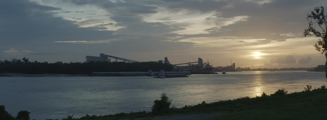 A boat on a river with trees buildings the sky and clouds in the background
