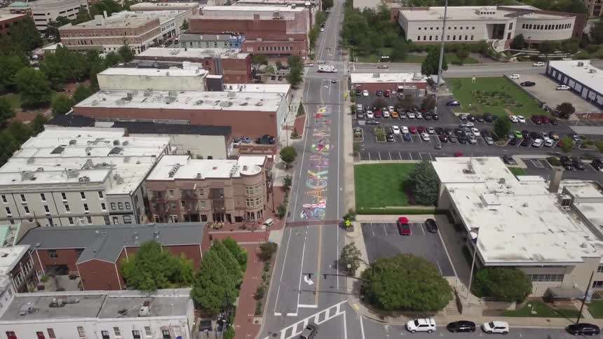 Cars driving on a city street with black lives matter written in chalk on the street