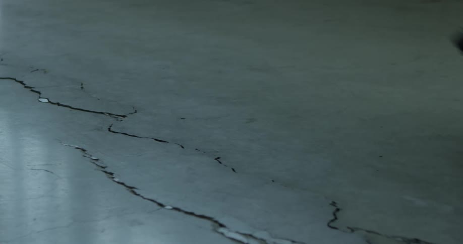 Man wearing pair of boots walking over a crack in a smooth floor