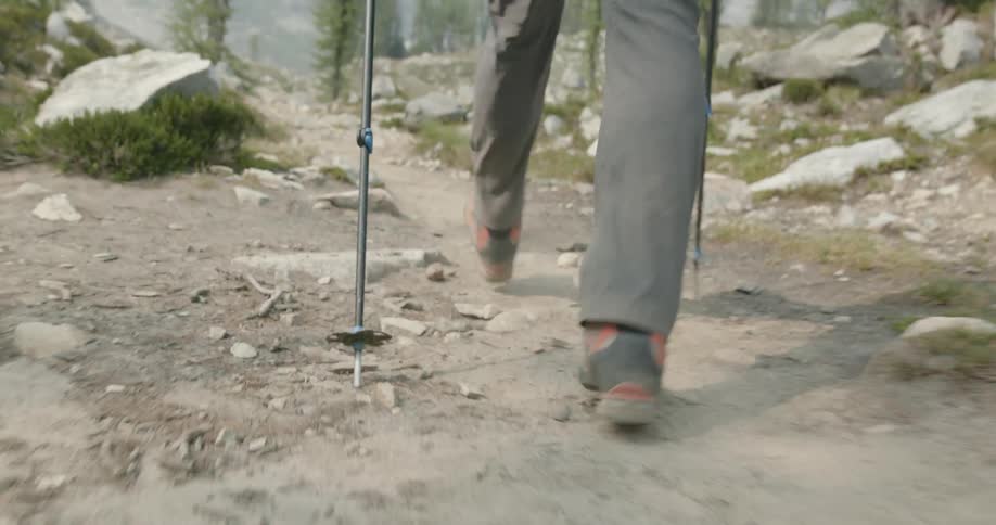 Person hikes along trail toward misty mountains