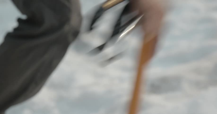 A man uses a walking stick and wears snow boots to hike through snow