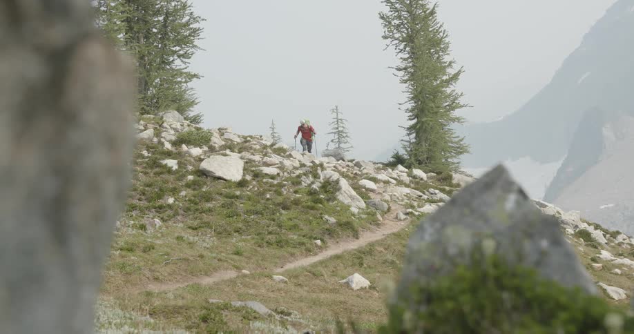 Man hiking up a rocky trail on a slope in the forest next to a cliff side at daytime