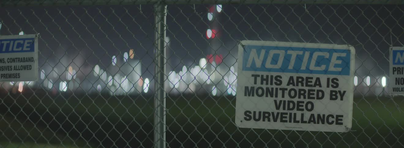 A fence with signs in front of a city skyline