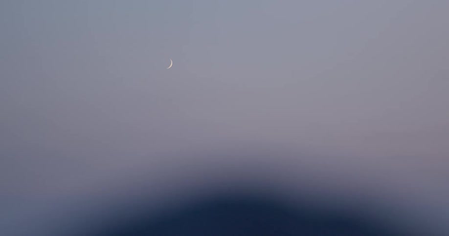 The moon is in the sky at dusk