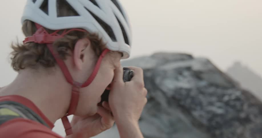 Man taking pictures at the top of a mountain with a small camera at daytime