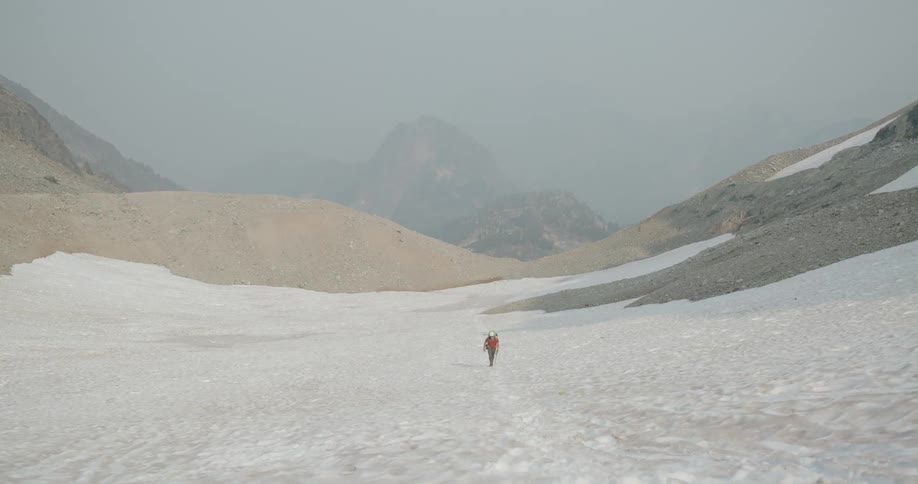 Person walking through the snow in a mountainous environment