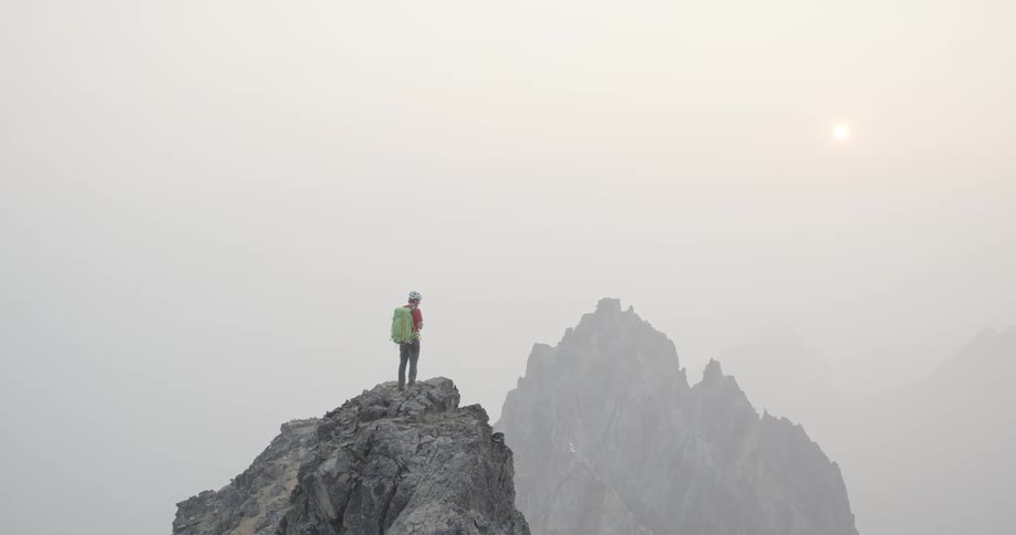 A man is climbing up a mountain at dusk
