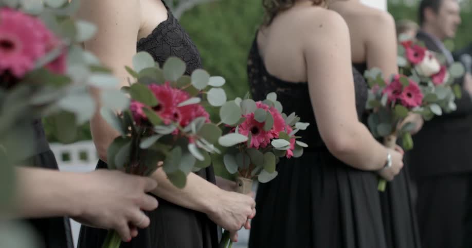 Bridesmaids are lined up with flowers in their hands