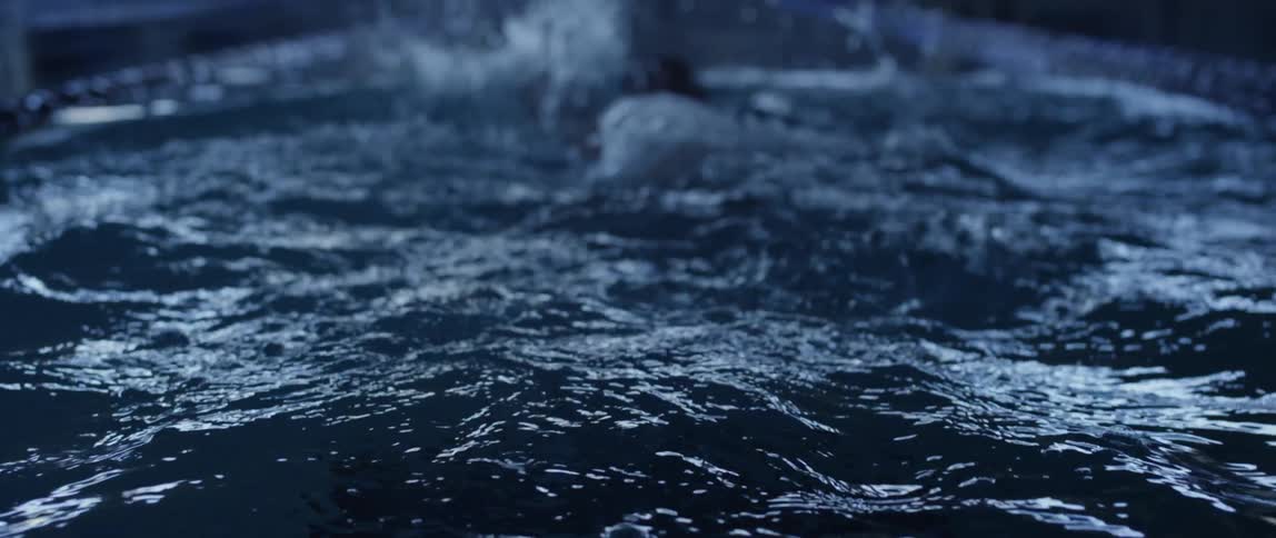 A swimmer pushes off the pool wall and swims