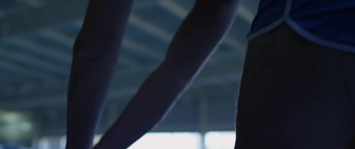 Man on top of a diving board getting ready to jump into a indoor pool at daytime
