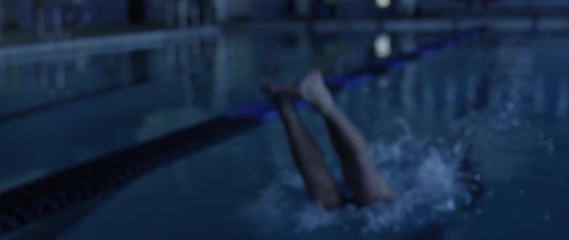 Swimmer uses trampoline jumps on an indoor olympic pool