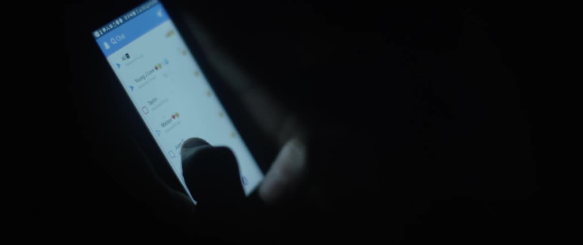 A person looking at and touching a smart phone in the dark