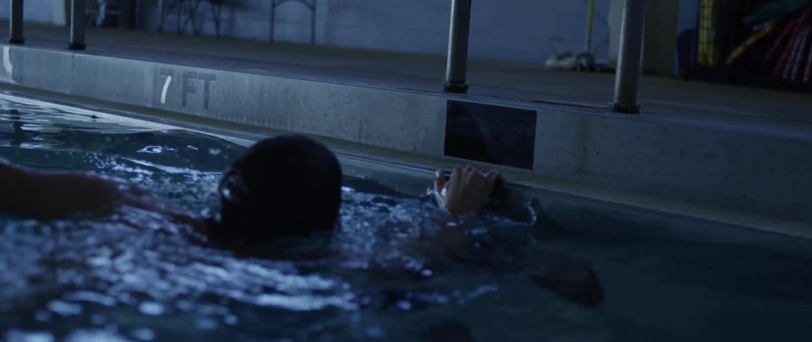 A man is swimming in a pool indoors
