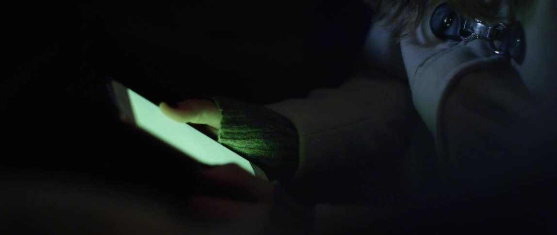 A person in a dark environment illuminated by the screen of a smartphone