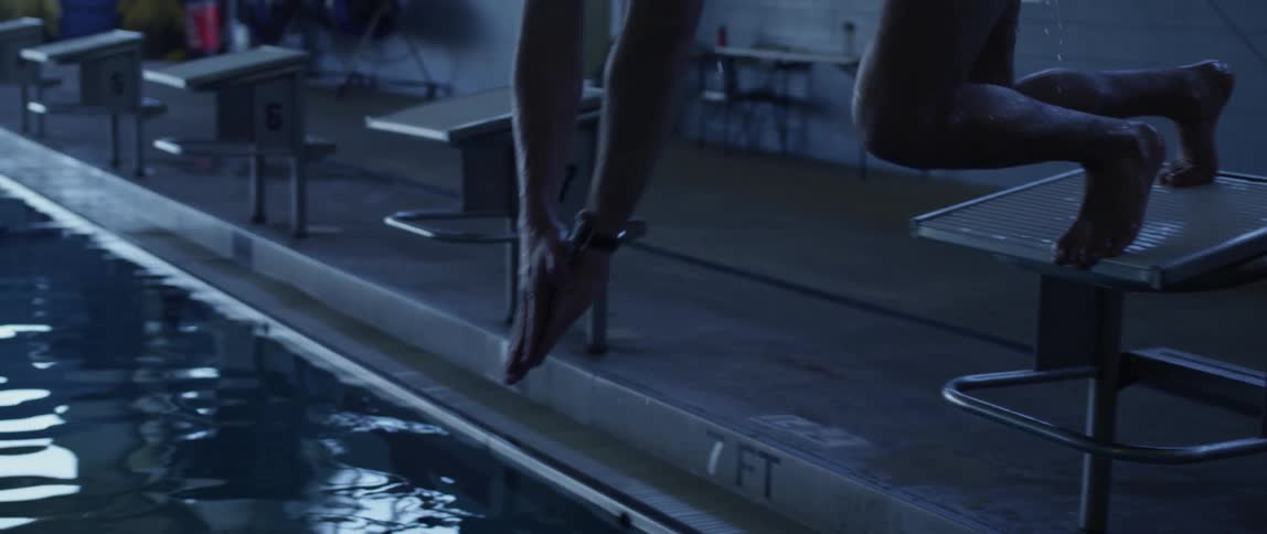 A man dives off the starting block and in to a pool