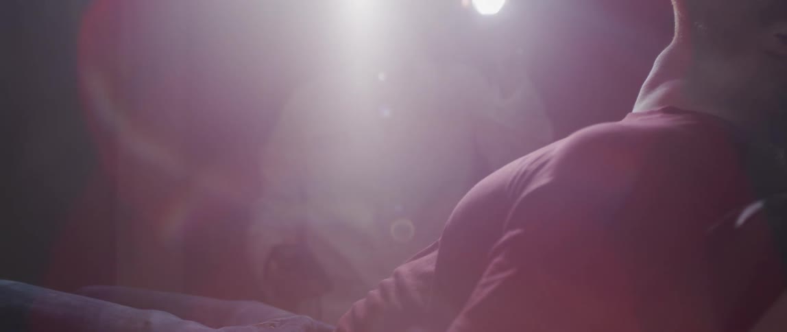 A woman holding a cell phone shines her flashlight over a man in a reclining chair