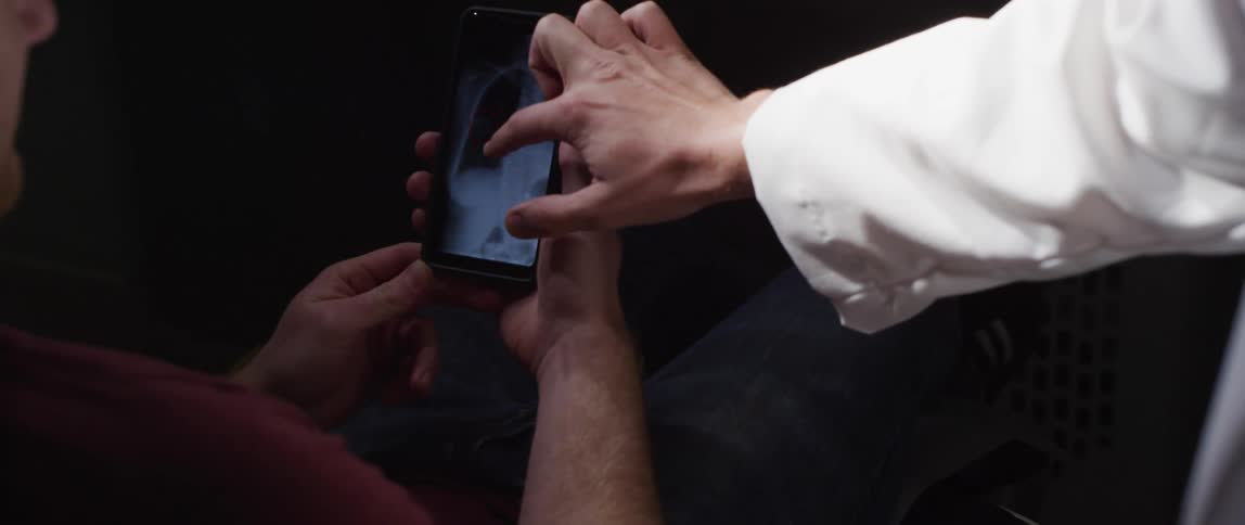 A doctor helps a man to view an x ray on a smartphone