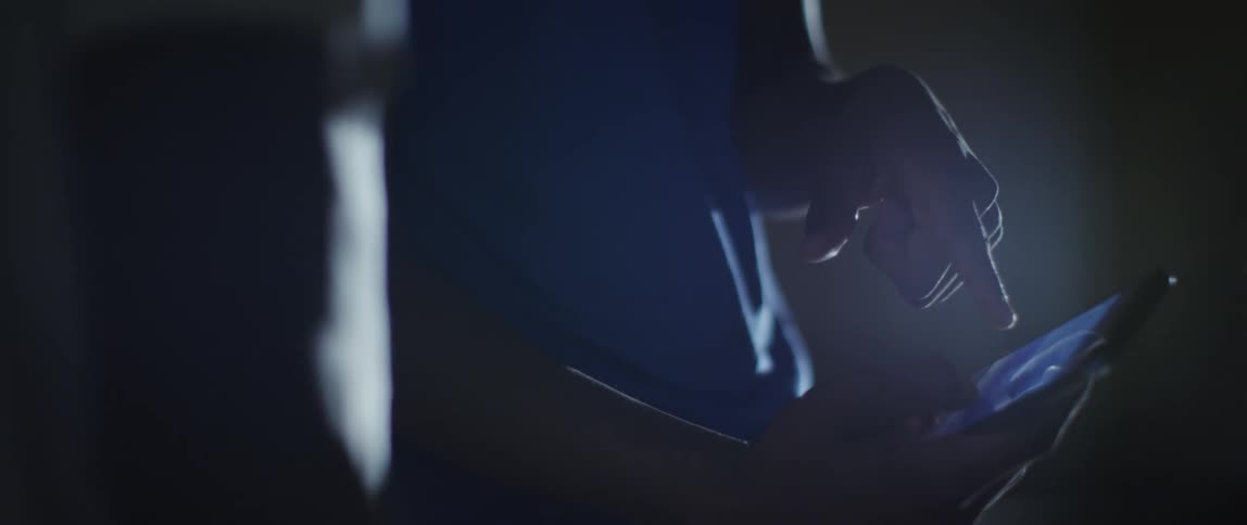 Hand swiping a screen on a smartphone in a dark room
