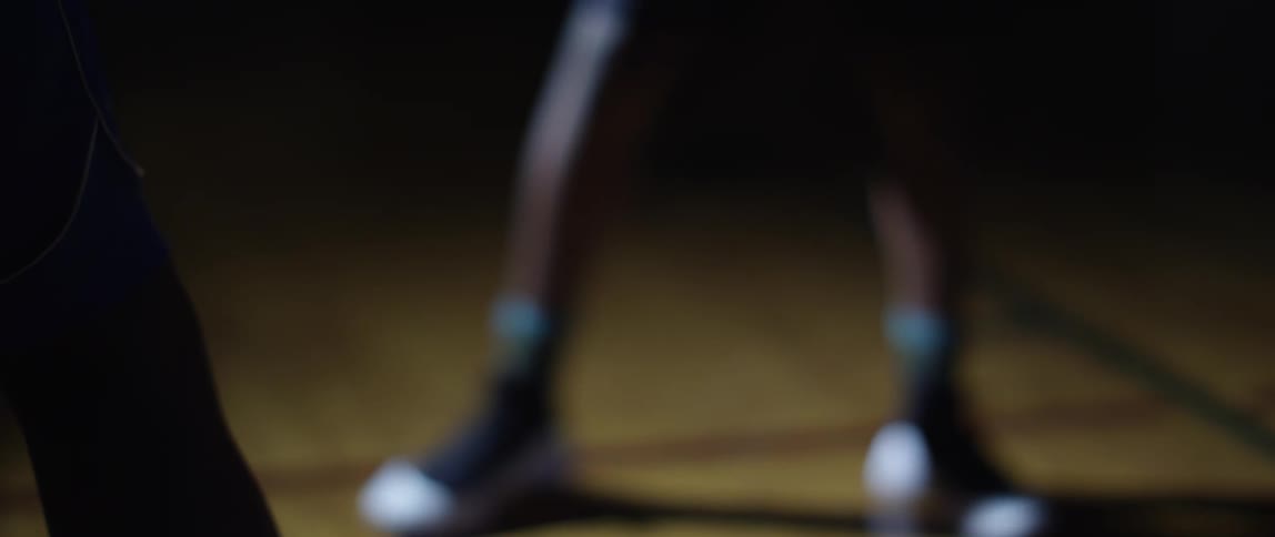Two basketball players facing each other in a dimly lit basketball court