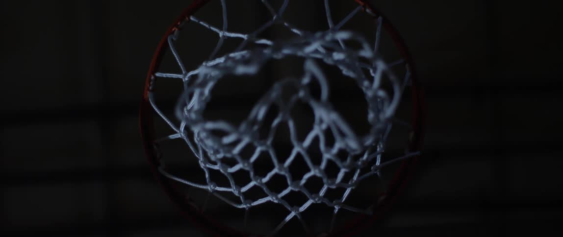A basketball is shot and swishes through a basketball hoop