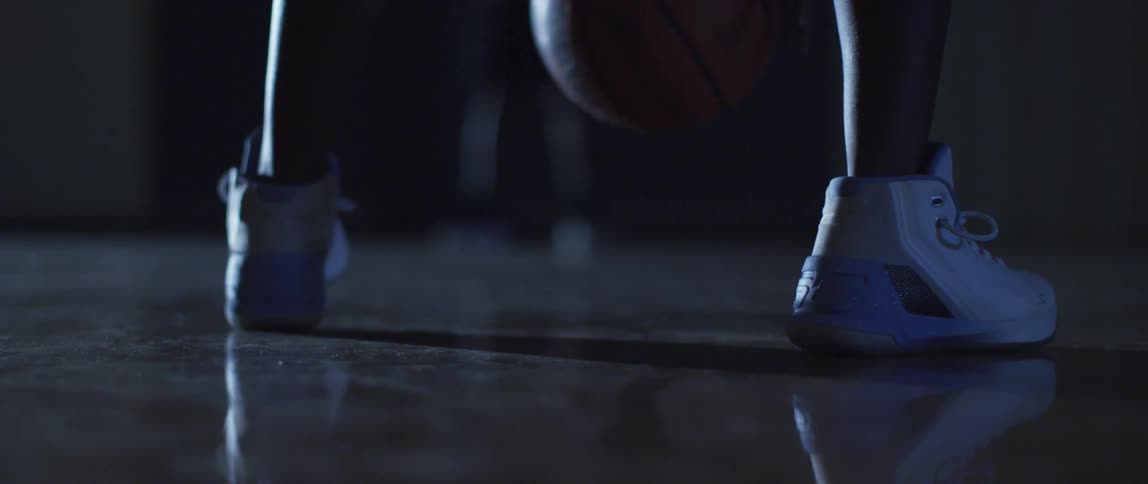 A person is dribbling a basketball indoors