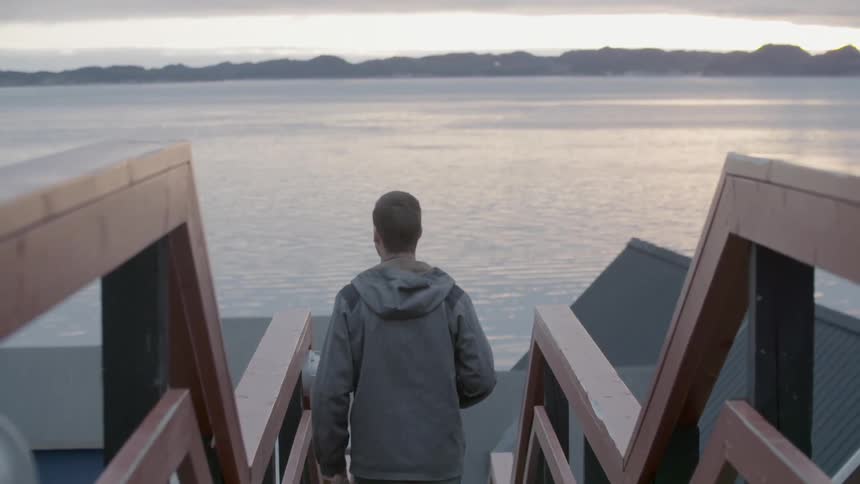 A man is walking done some steps near a lake